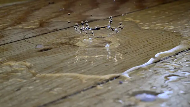 Close view of water pooling in the seams of wood plank flooring